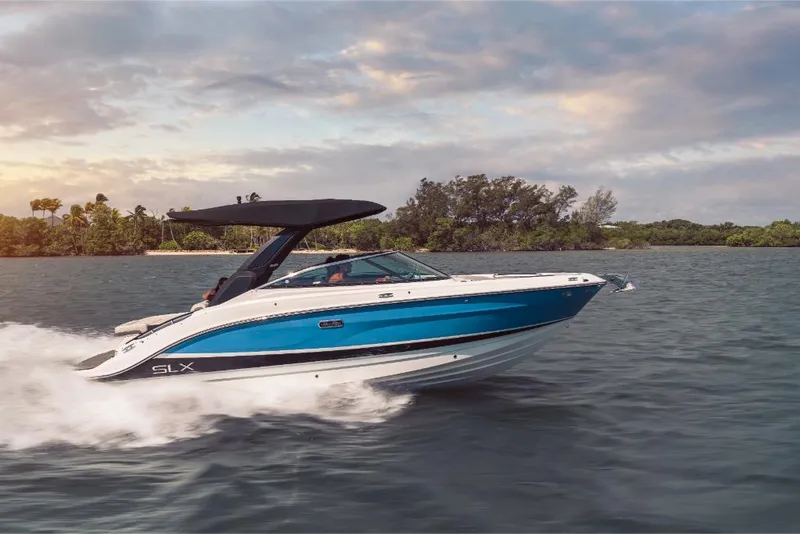 Slide: The Image of 2023 Sea Ray SLX 260 boat cruising on water at sunset. - 2