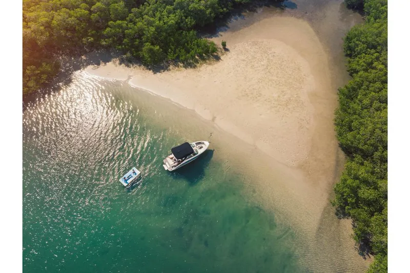 Slide: The Image of Aerial view of 2023 Sea Ray SLX 260 boat anchored near a sandy beach and lush greenery. - 20