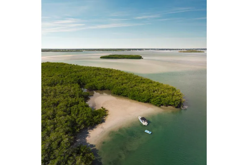 Slide: The Image of Aerial view of a 2023 Sea Ray SLX 260 boat anchored near a lush, green island. - 21