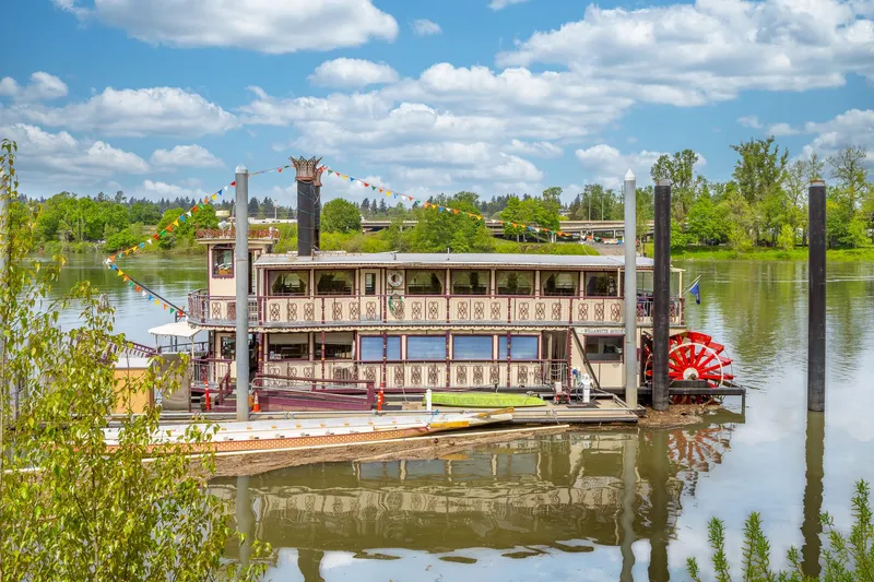 The Image of Vintage 1990 Howdy Eidelman Sternwheeler on a scenic river with lush greenery. - 1