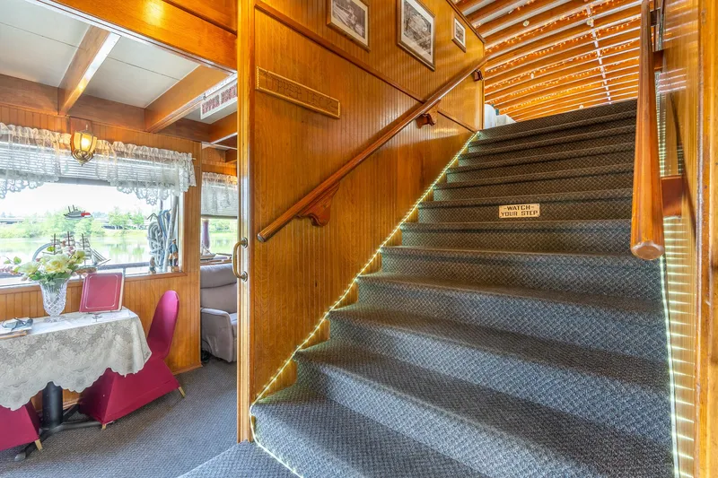 Slide: The Image of Interior of 1990 Custom Howdy Eidelman Sternwheeler, featuring carpeted stairs and dining area. - 10