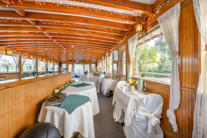 Slide: The Image of Elegant interior of 1990 Custom Howdy Eidelman Sternwheeler, featuring wooden decor and draped tables. - 23