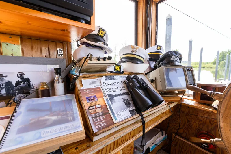 Slide: The Image of Pilothouse interior with captain hats, binoculars, and nautical charts on a 1990 Howdy Eidelman Sternwheeler. - 36