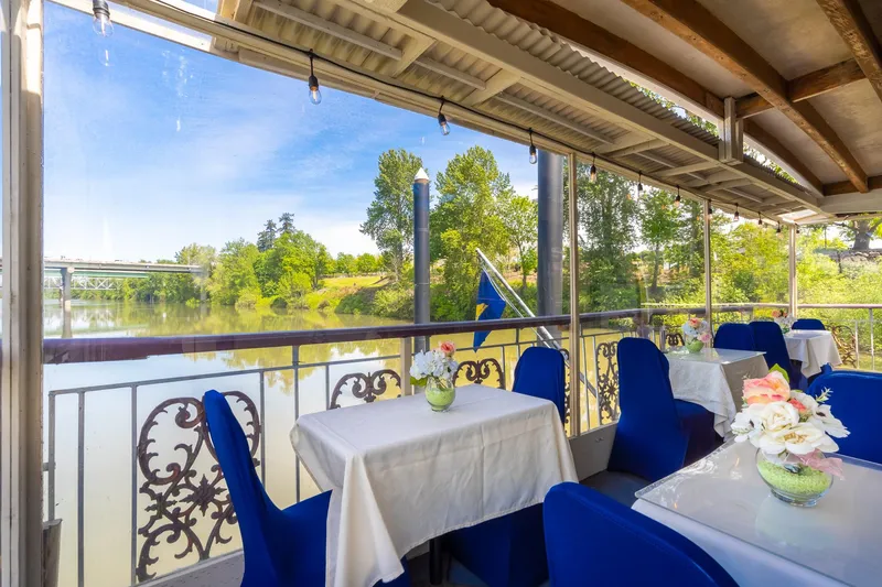 Slide: The Image of Elegant dining area on 1990 Howdy Eidelman Sternwheeler, overlooking serene river and lush greenery. - 49