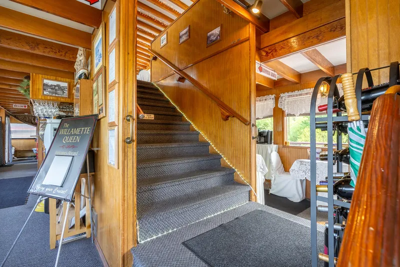Slide: The Image of Interior of 1990 Howdy Eidelman Sternwheeler, featuring wooden staircase and dining area. - 9
