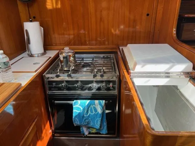 Slide: The Image of 1979 Palmer Johnson New York 40 Sloop kitchen with stove, towel, and wooden cabinetry. - 18