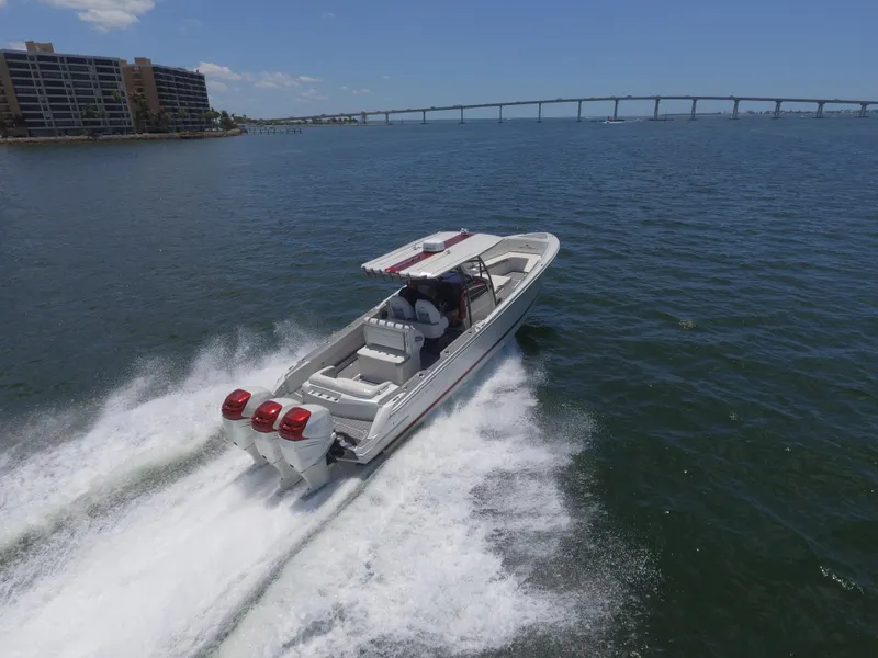 Slide: The Image of 2017 Nor-Tech 390 Sport boat speeding on water near a bridge. - 12