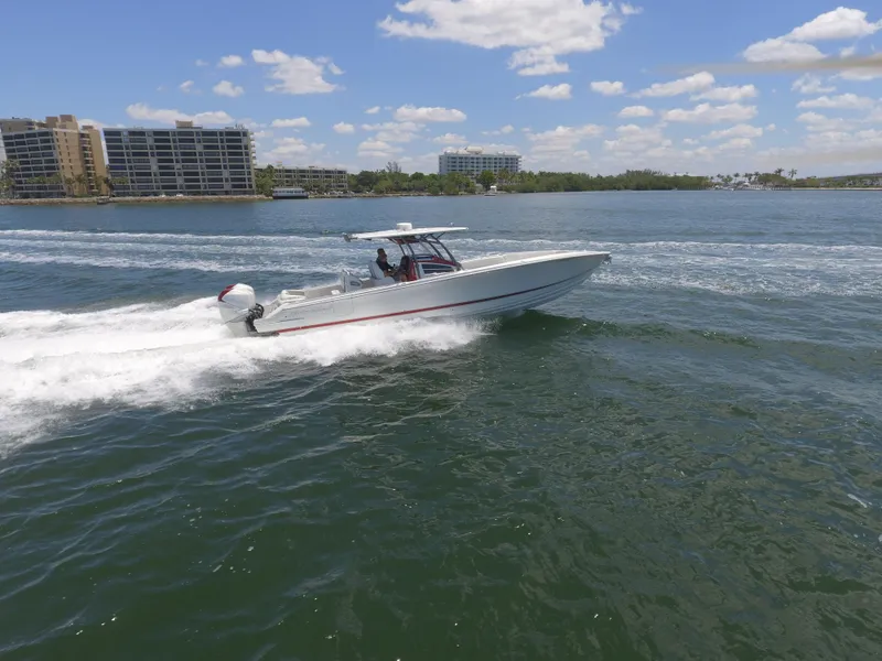 Slide: The Image of 2017 Nor-Tech 390 Sport boat cruising on a sunny day near coastal buildings. - 14