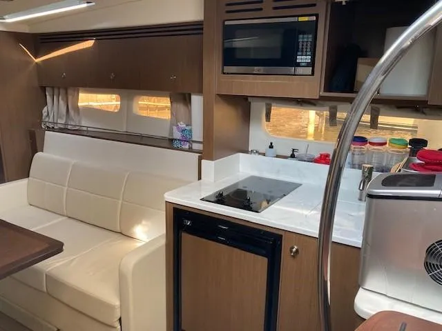 Slide: The Image of Interior of 2019 Sea Ray 350 Sundancer with kitchenette and seating area. - 10