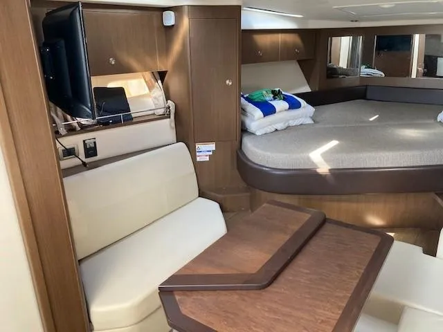 Slide: The Image of 2019 Sea Ray 350 Sundancer cabin interior with bed, seating, and TV. - 11