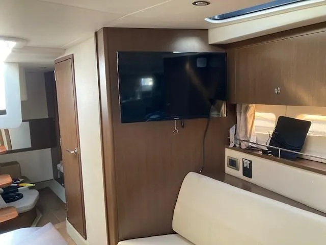 Slide: The Image of Interior of 2019 Sea Ray 350 Sundancer with TV, seating, and wooden cabinetry. - 12