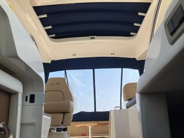 Slide: The Image of Interior of 2019 Sea Ray 350 Sundancer boat with blue canopy and beige seating. - 17