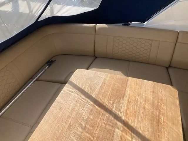 Slide: The Image of Interior seating area of a 2019 Sea Ray 350 Sundancer with beige upholstery and wooden table. - 3