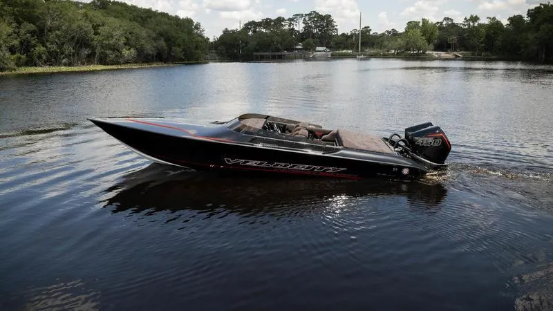 The Image of 2024 Velocity VR1 speedboat on a calm lake with lush greenery in the background. - 1