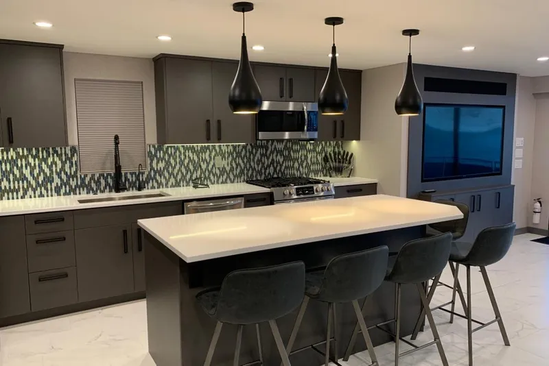 Slide: The Image of Modern kitchen with dark cabinets, island seating, pendant lights, and patterned backsplash. Adonia Utopia Trip 2019. - 7