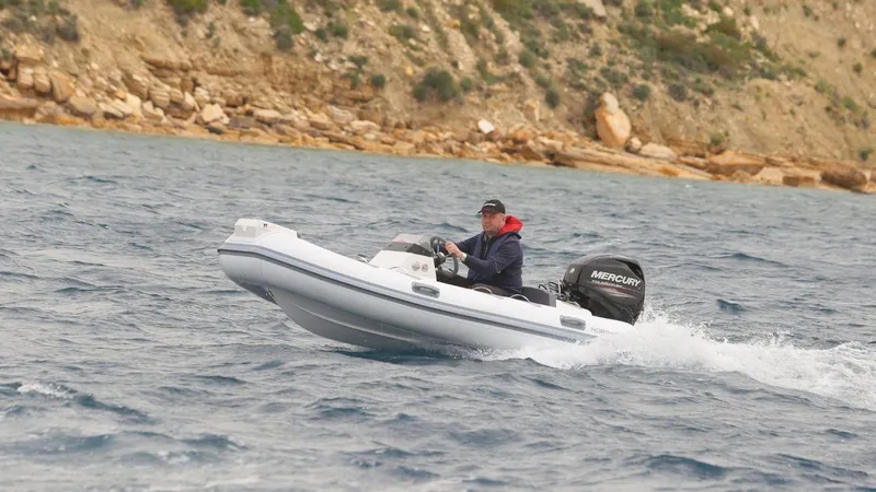 Slide: The Image of 2021 Northstar Axis 3.4 boat cruising on water near rocky shoreline. - 2