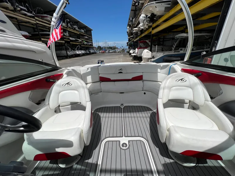 Slide: The Image of 2015 Monterey 224FSX boat interior with white and red seating, docked at a marina. - 15