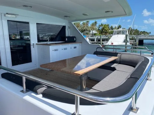 Slide: The Image of Luxurious 1990 Broward Raised Pilothouse MY yacht with outdoor seating and table, docked by palm trees. - 11