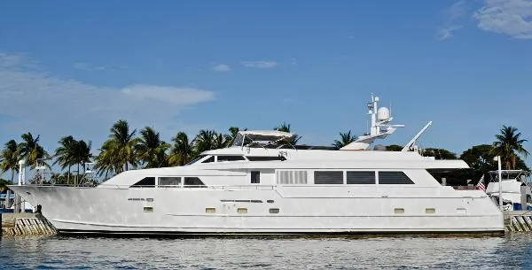 Slide: The Image of Luxury 1990 Broward Raised Pilothouse MY yacht docked by palm trees under clear sky. - 2
