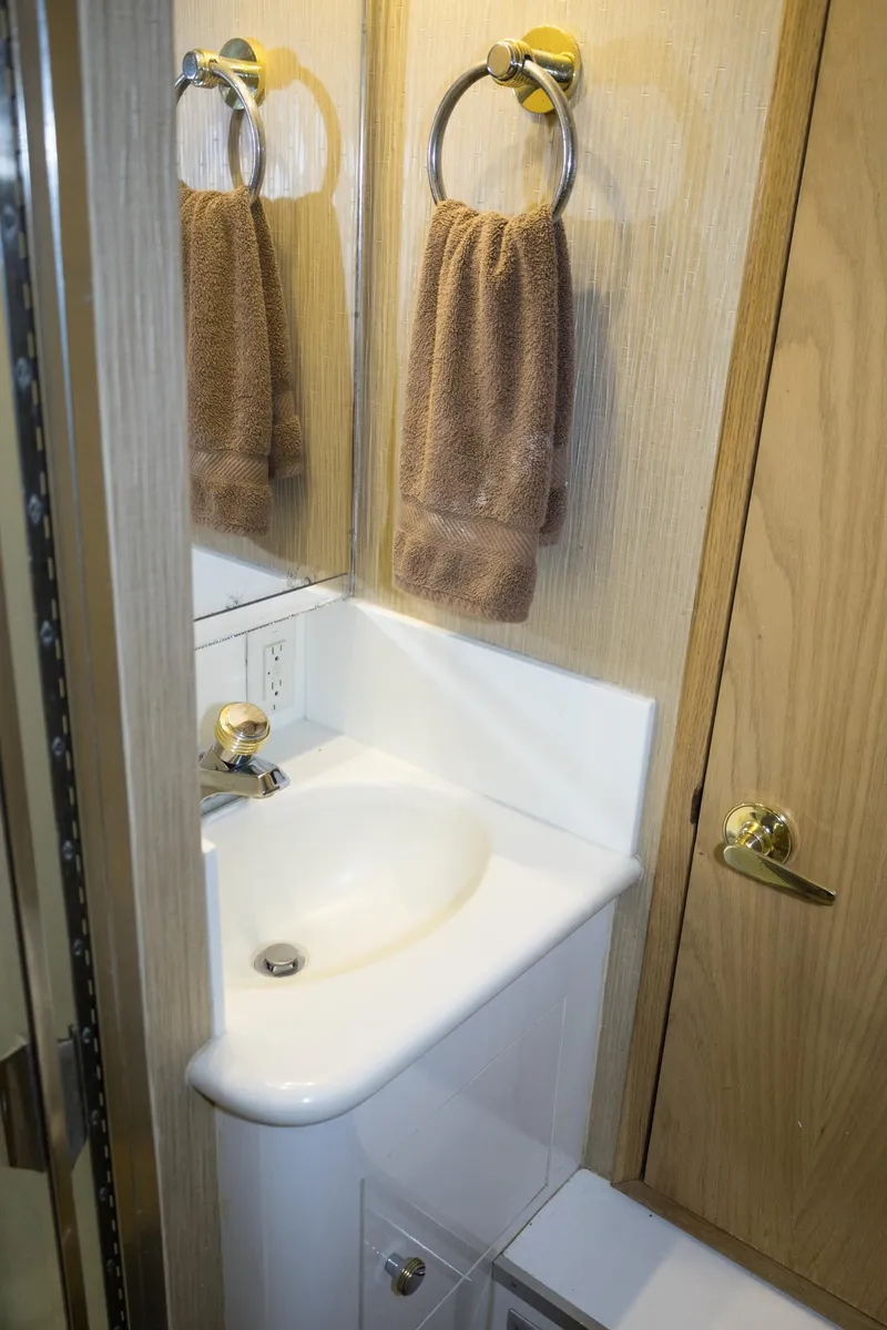Slide: The Image of Bathroom sink area in a 1997 Hatteras 65 Convertible yacht, featuring a towel ring and wooden cabinetry. - 19