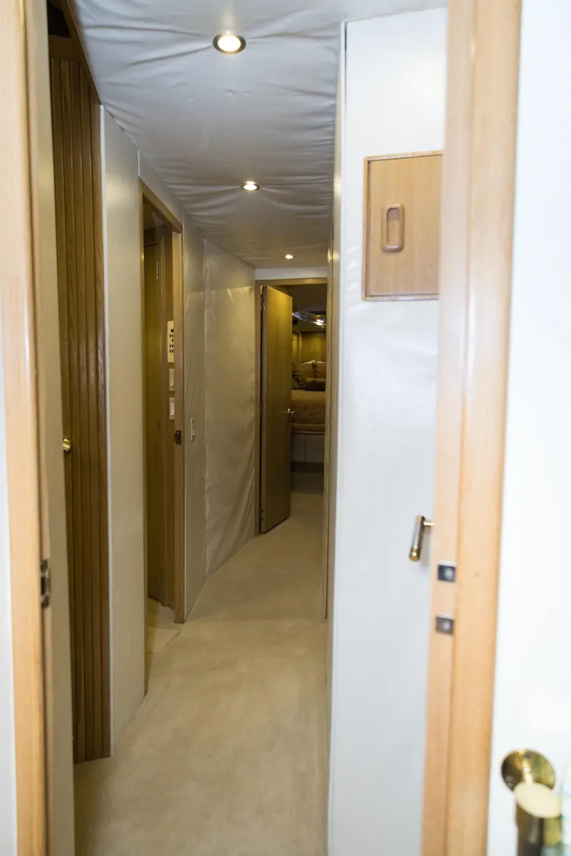 Slide: The Image of Interior hallway of a 1997 Hatteras 65 Convertible yacht, featuring wood accents and soft lighting. - 21