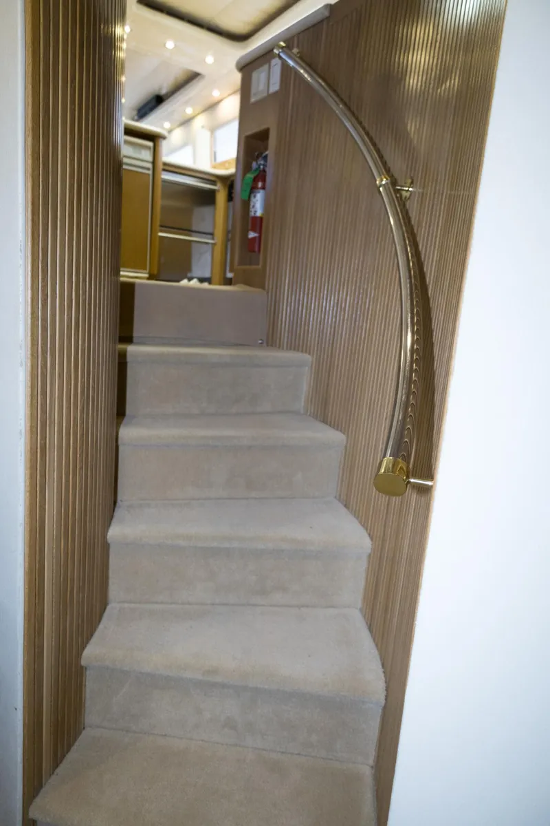 Slide: The Image of Staircase inside 1997 Hatteras 65 Convertible yacht with elegant wooden paneling and brass handrail. - 35