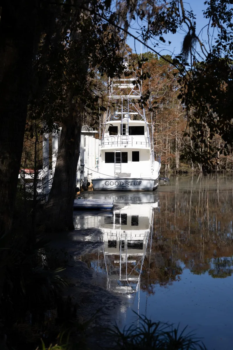 Slide: The Image of 1997 Hatteras 65 Convertible yacht reflected on a serene, wooded lake. - 42