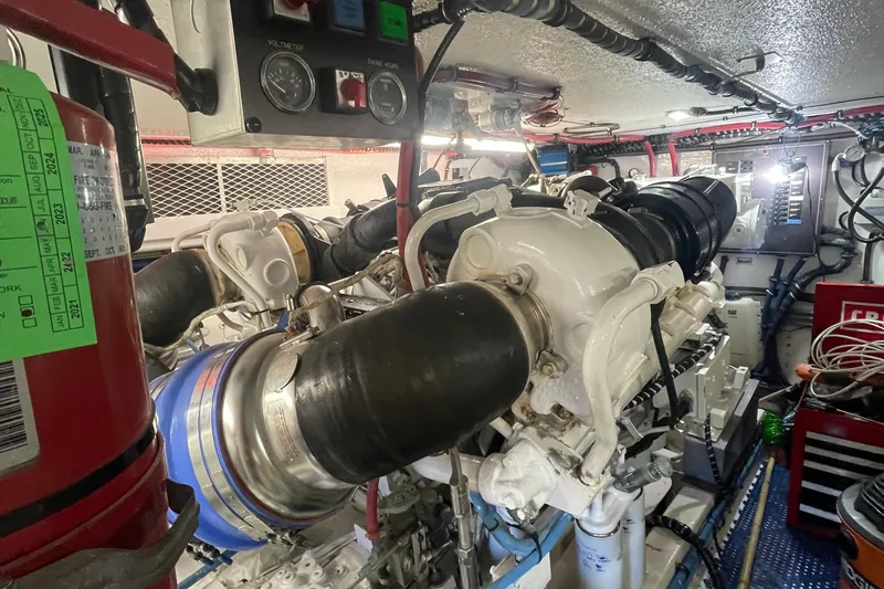 Slide: The Image of Engine room of 1997 Hatteras 65 Convertible yacht, featuring complex machinery and control panels. - 44