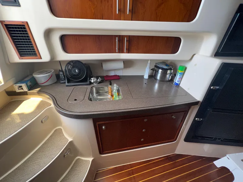Slide: The Image of 2006 Grady-White 360 Express cabin kitchen with sink, wooden cabinets, and stairs. - 19
