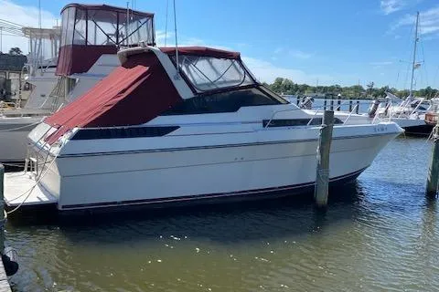 The Image of 1990 Silverton 34 Express boat docked at a marina with red canopy. - 0