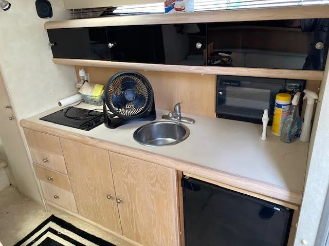 Slide: The Image of 1990 Silverton 34 Express boat kitchen with sink, stove, fan, and storage cabinets. - 12