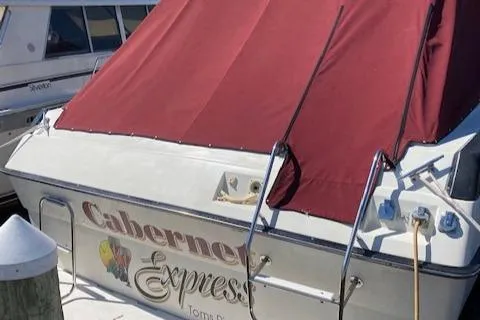 Slide: The Image of 1990 Silverton 34 Express boat with maroon cover docked at marina. - 18