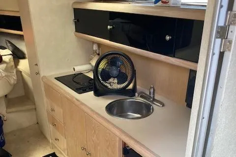 Slide: The Image of Compact kitchen area in a 1990 Silverton 34 Express boat with sink, stove, and fan. - 23