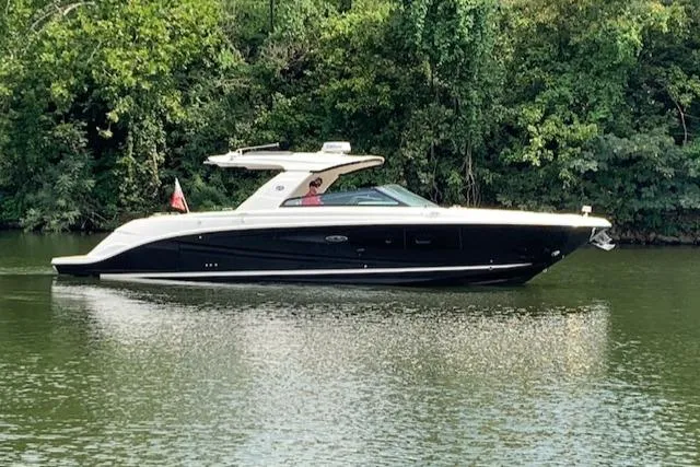 Slide: The Image of 2020 Sea Ray 400 SLX luxury boat cruising on a serene river. - 2