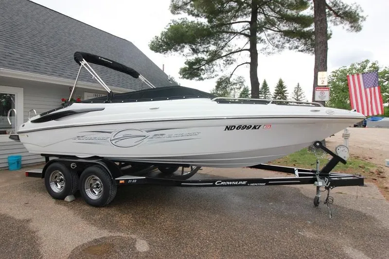 The Image of 2015 Crownline 21 SS boat on a trailer, parked outdoors near a house. - 0