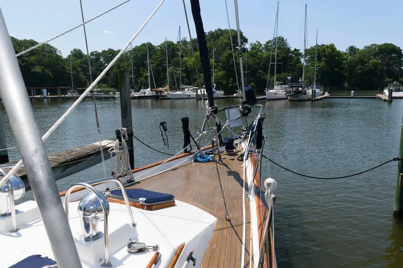 Slide: The Image of 1988 Tayana 52 sailboat docked in a serene marina with other boats. - 14