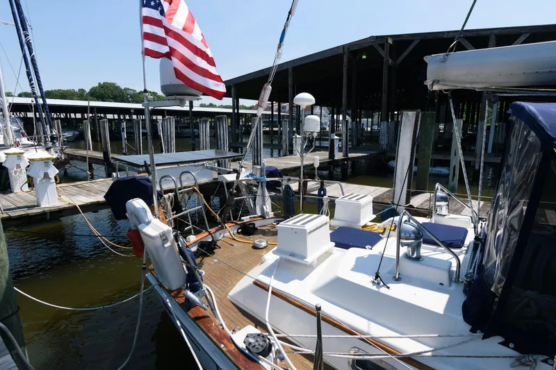 Slide: The Image of 1988 Tayana 52 sailboat docked at marina with American flag. - 17