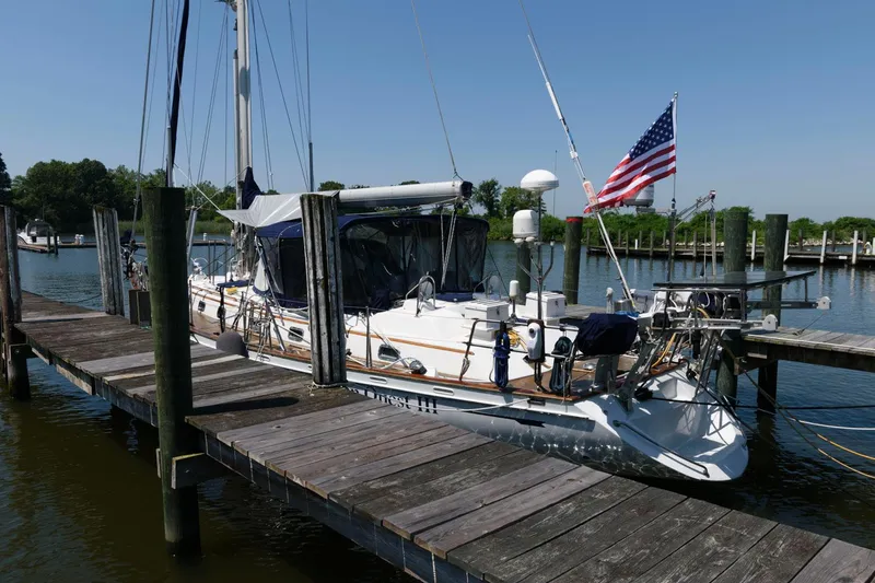 Slide: The Image of 1988 Tayana 52 sailboat docked with American flag. - 23