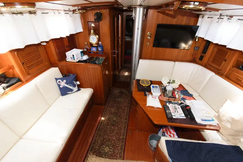 Slide: The Image of Interior of 1988 Tayana 52 yacht with white seating, wooden finishes, and a mounted TV. - 28