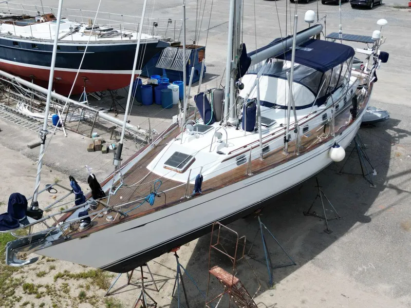 Slide: The Image of 1988 Tayana 52 sailboat on dry dock, featuring sleek design and blue canopy. - 3