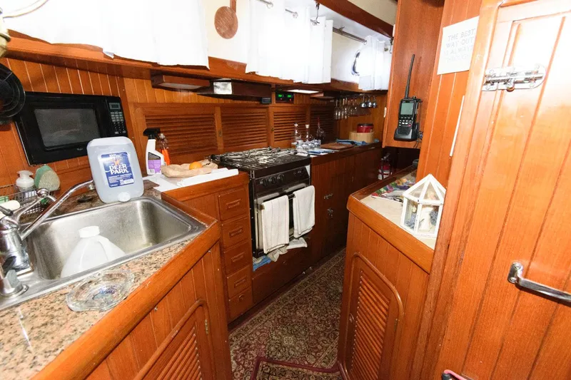 Slide: The Image of 1988 Tayana 52 yacht kitchen with wooden cabinetry, granite countertops, and modern appliances. - 32