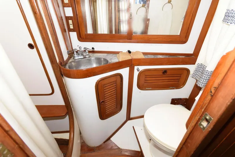 Slide: The Image of 1988 Tayana 52 yacht bathroom with sink, toilet, wooden cabinets, and mirror. - 38