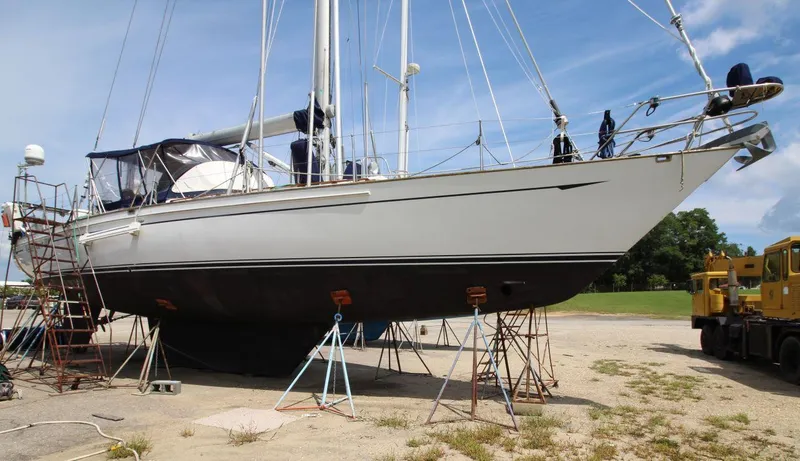 Slide: The Image of 1988 Tayana 52 sailboat on dry dock, supported by stands, under clear blue sky. - 4