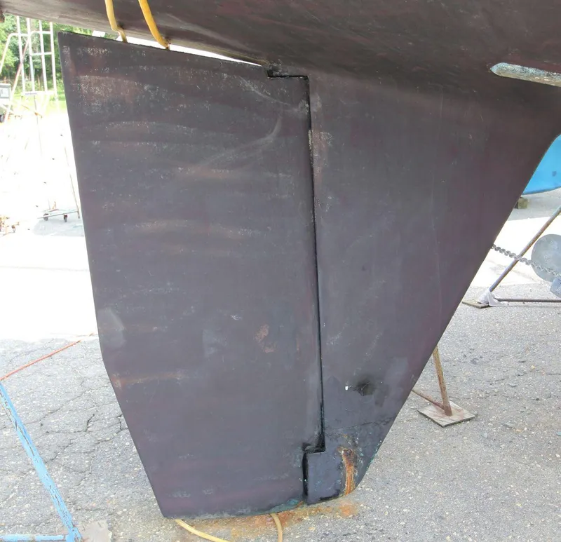 Slide: The Image of Rudder of 1988 Tayana 52 sailboat on dry dock, showing wear and maintenance needs. - 47