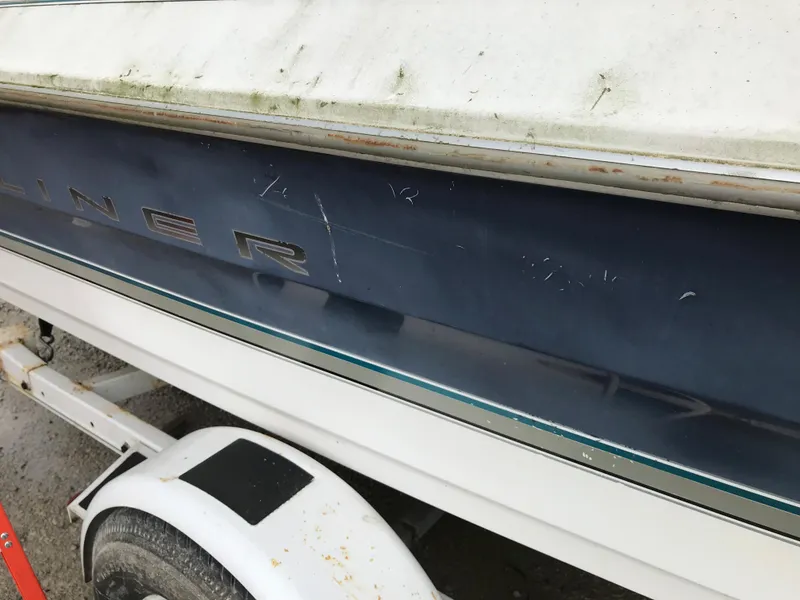Slide: The Image of 1997 Bayliner 2050 boat on trailer, showing side view with visible wear. - 12