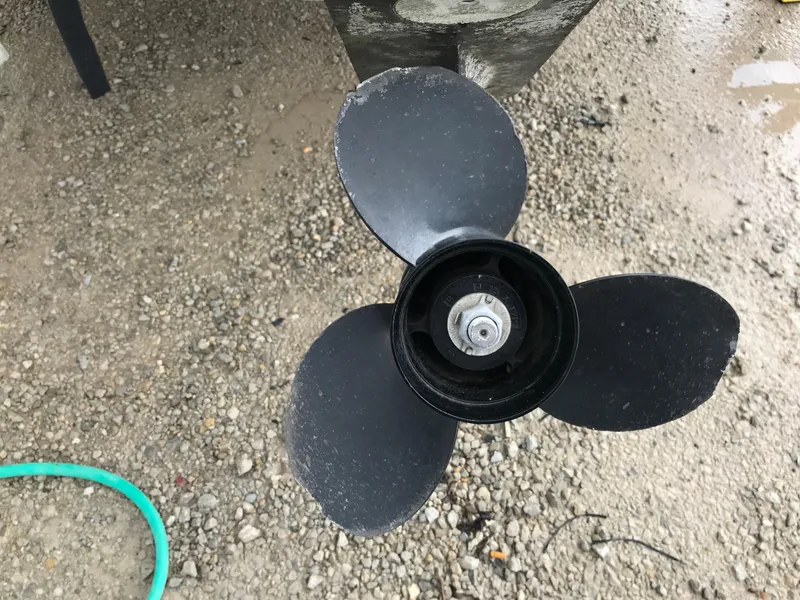 Slide: The Image of Close-up of a 1997 Bayliner 2050 boat propeller on gravel. - 2