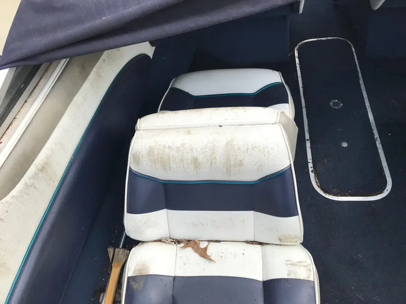 Slide: The Image of 1997 Bayliner 2050 boat interior with worn, white and blue seats. - 23