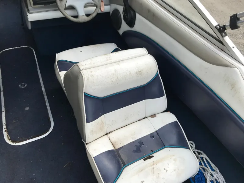 Slide: The Image of 1997 Bayliner 2050 boat interior with worn white and blue seats. - 24