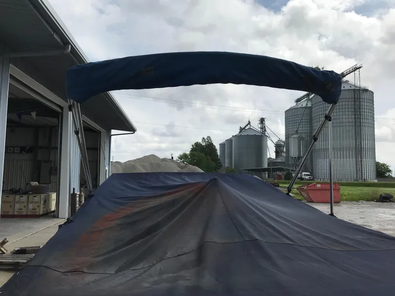 Slide: The Image of 1997 Bayliner 2050 boat with a blue cover in an industrial area. - 4