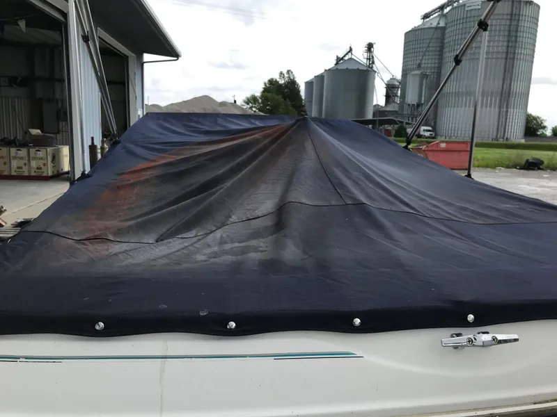 Slide: The Image of 1997 Bayliner 2050 boat with black cover in a rural storage area. - 5